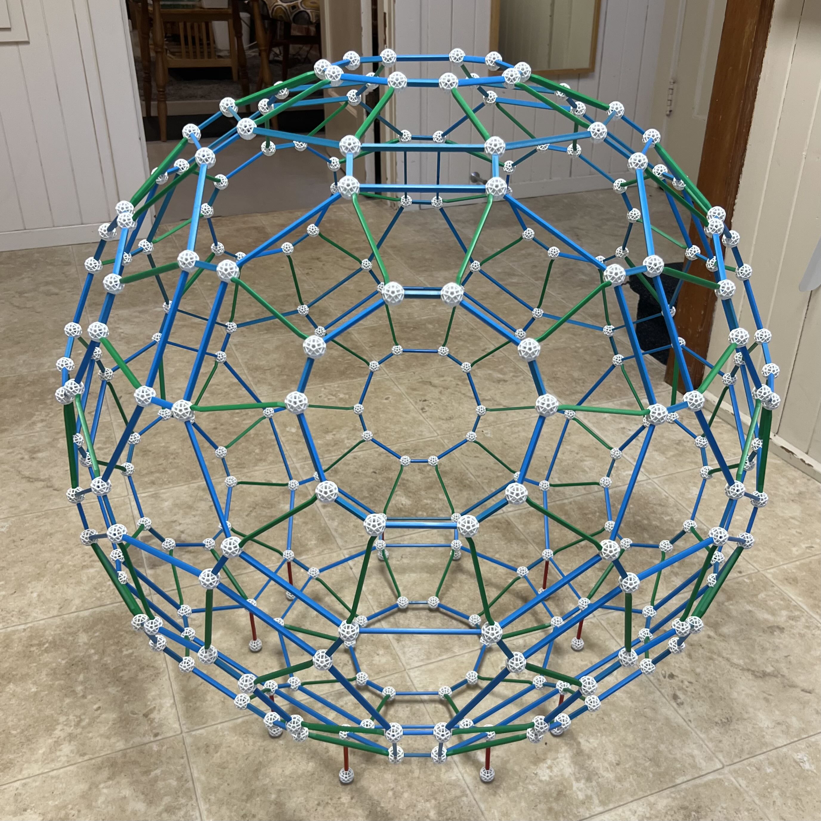 The 240-ball Zometool shell on the floor, with blue and green struts and red support legs